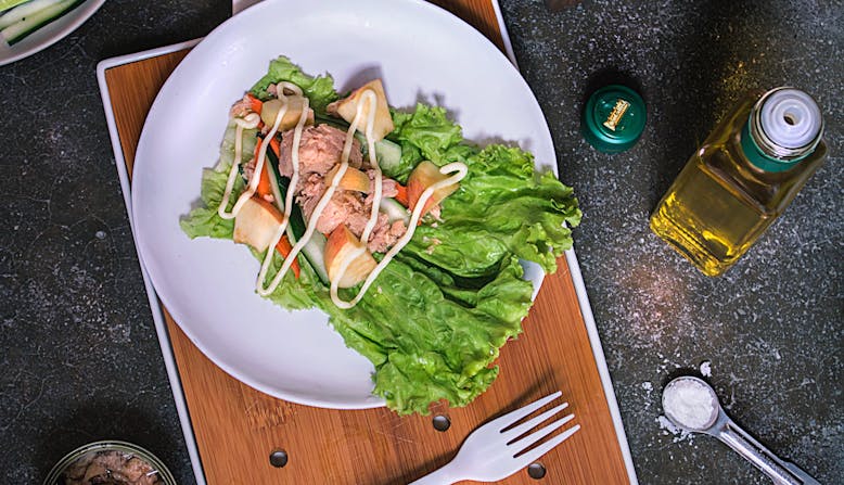 A plate with tuna salad surrounded by ingredients and cooking supplies.