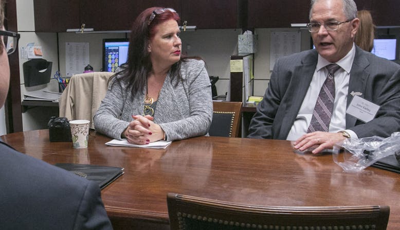 John Espers talks to others about his medical bills around a table.