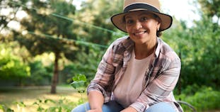 A woman gardening holding a plant.