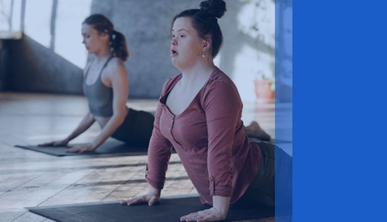 Two women stretch in a yoga studio.