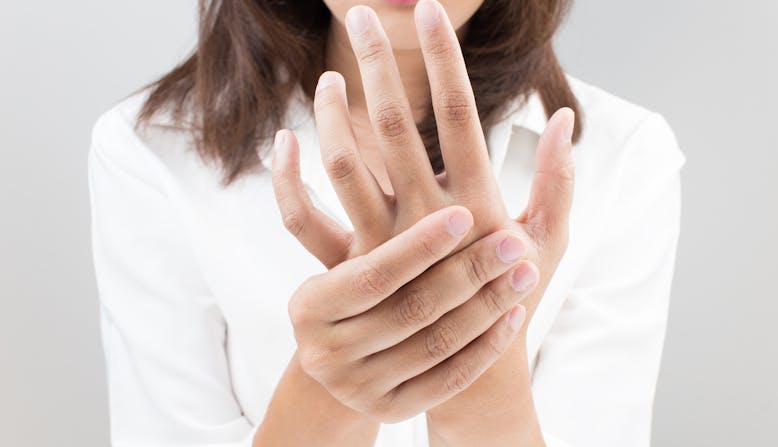 Acute pain in a woman's hand. A woman shown holding one hand with her other.