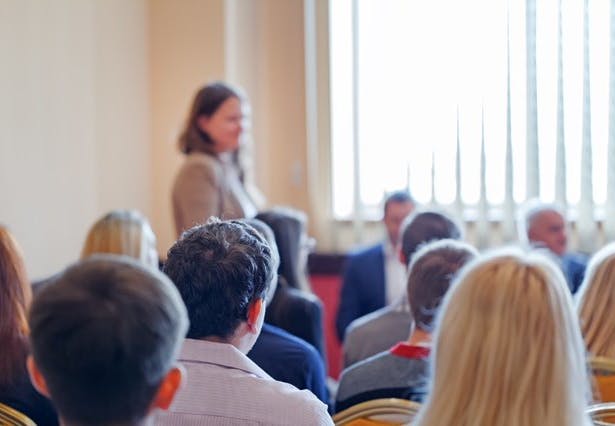 An audience listening to a panel discussion in a brightly lit room.