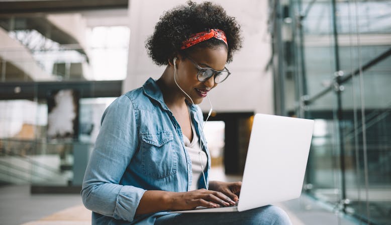A young woman sits in a building working on her computer.