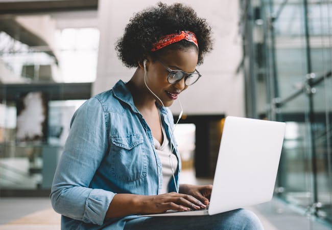 A young woman sits in a building working on her computer.