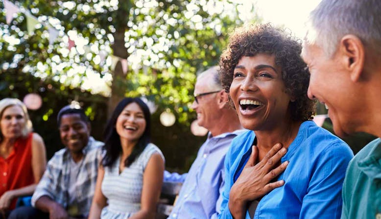 A group of people converse and laugh outside.