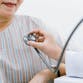 Young doctor using stethoscope to exam senior patient's heart.
