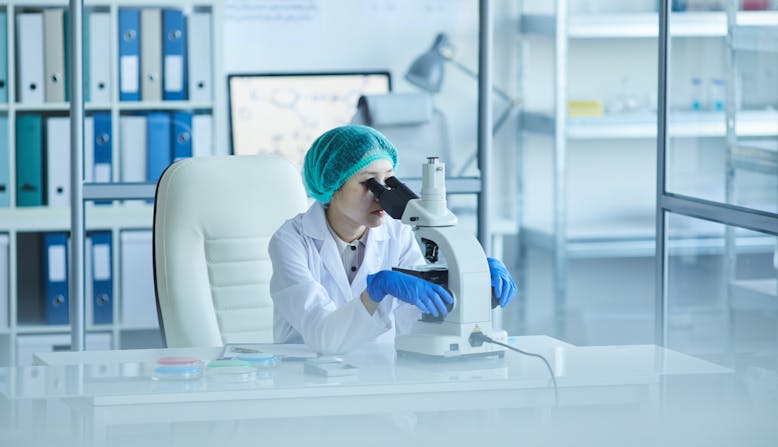 A female researcher looks into a microscope