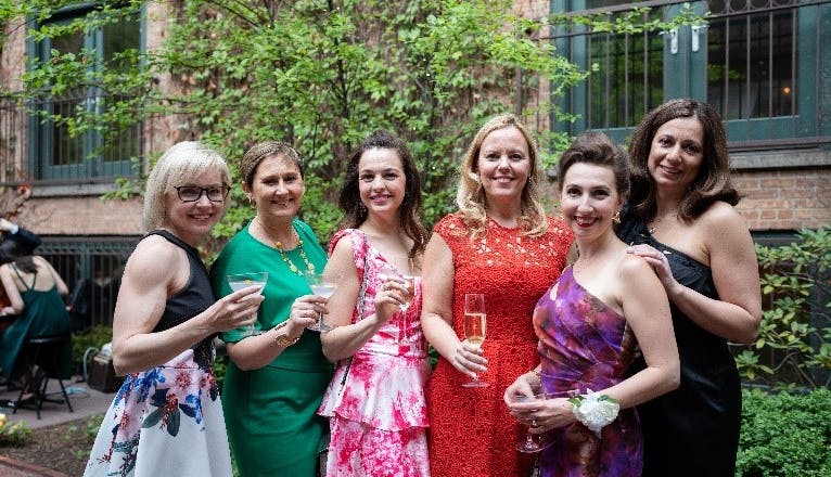 A group of women in floral dresses outside at an NPF cocktail event.