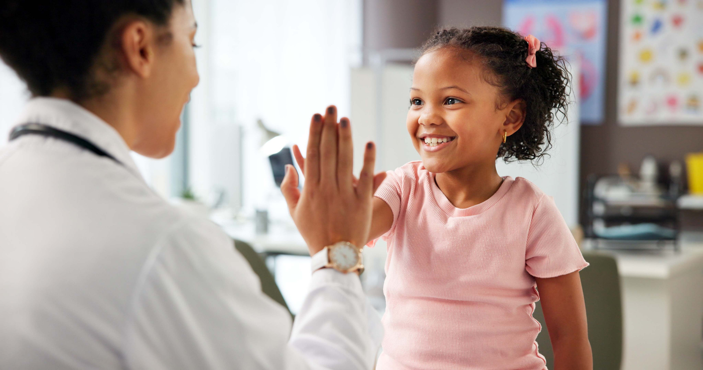 A doctor high-fives with a little girl in a doctor's office.