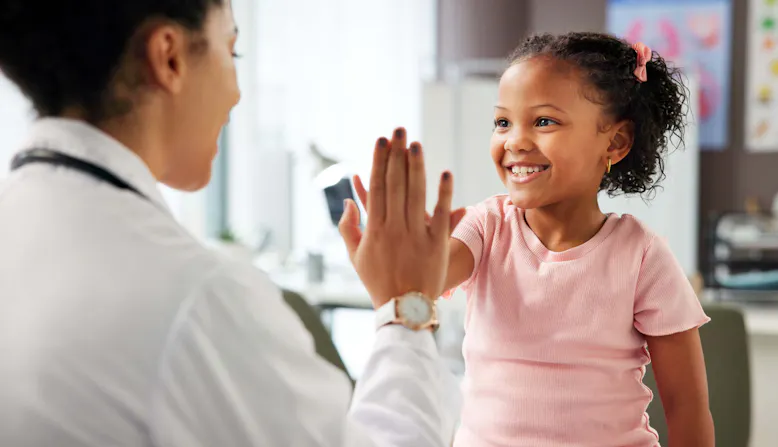 A doctor high-fives with a little girl in a doctor's office.