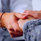 Doctor's hands clasping a patient's hands in support.