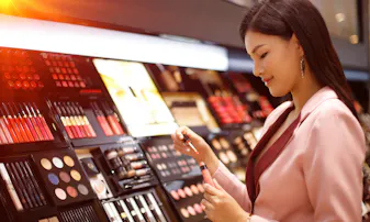 A woman looks at lip color in a cosmetic makeup store.