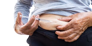 A person injects their stomach with a syringe.