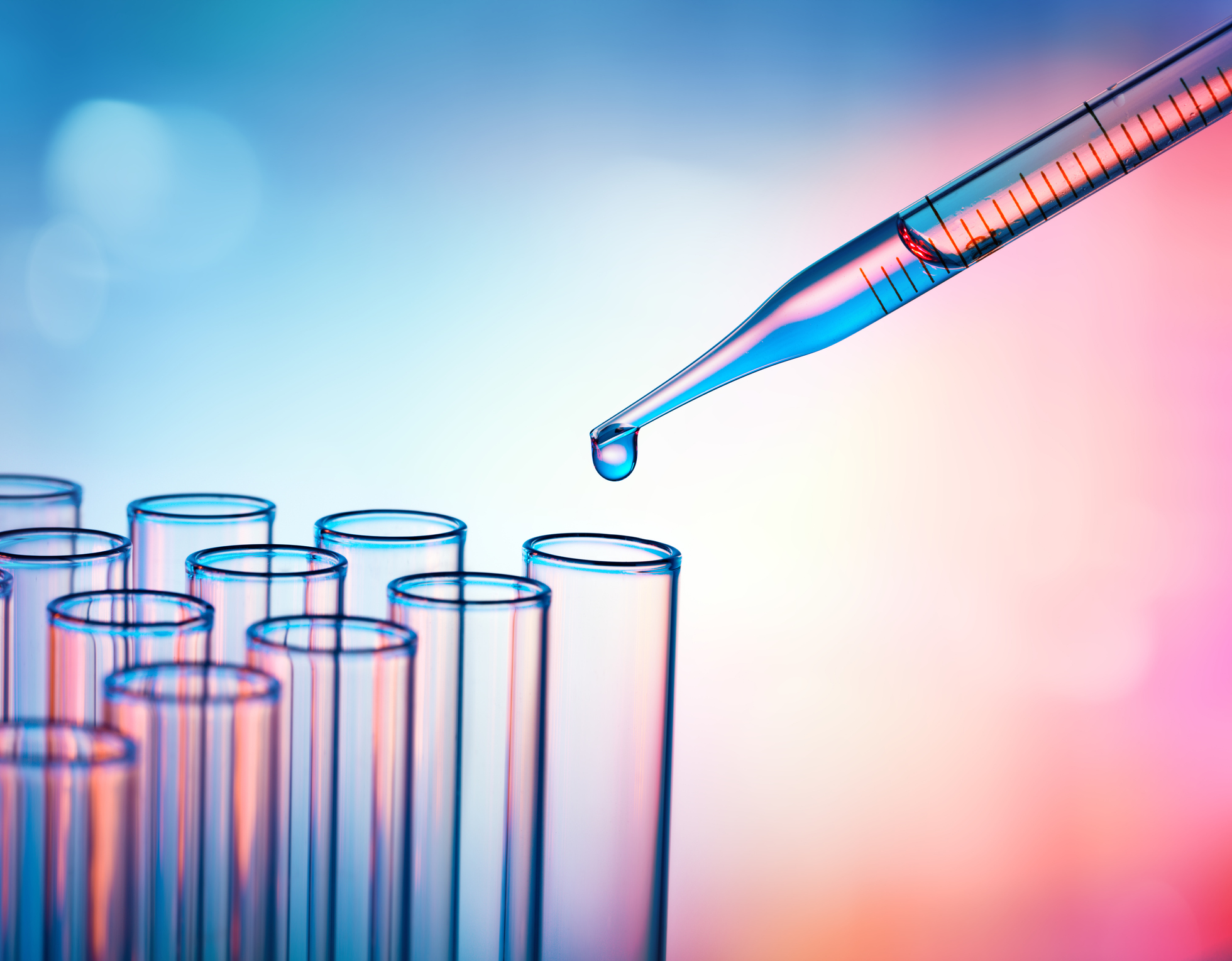 A pipette with liquid over test tubes. Cure concept.