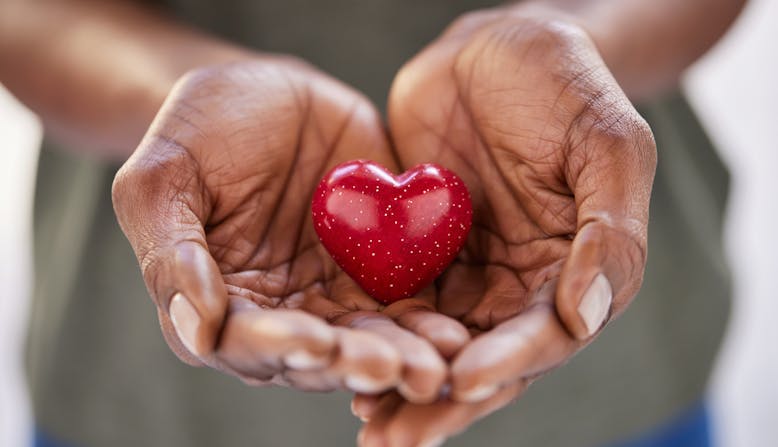 A person is holding their hands out together, cupping a small heart-shaped object.