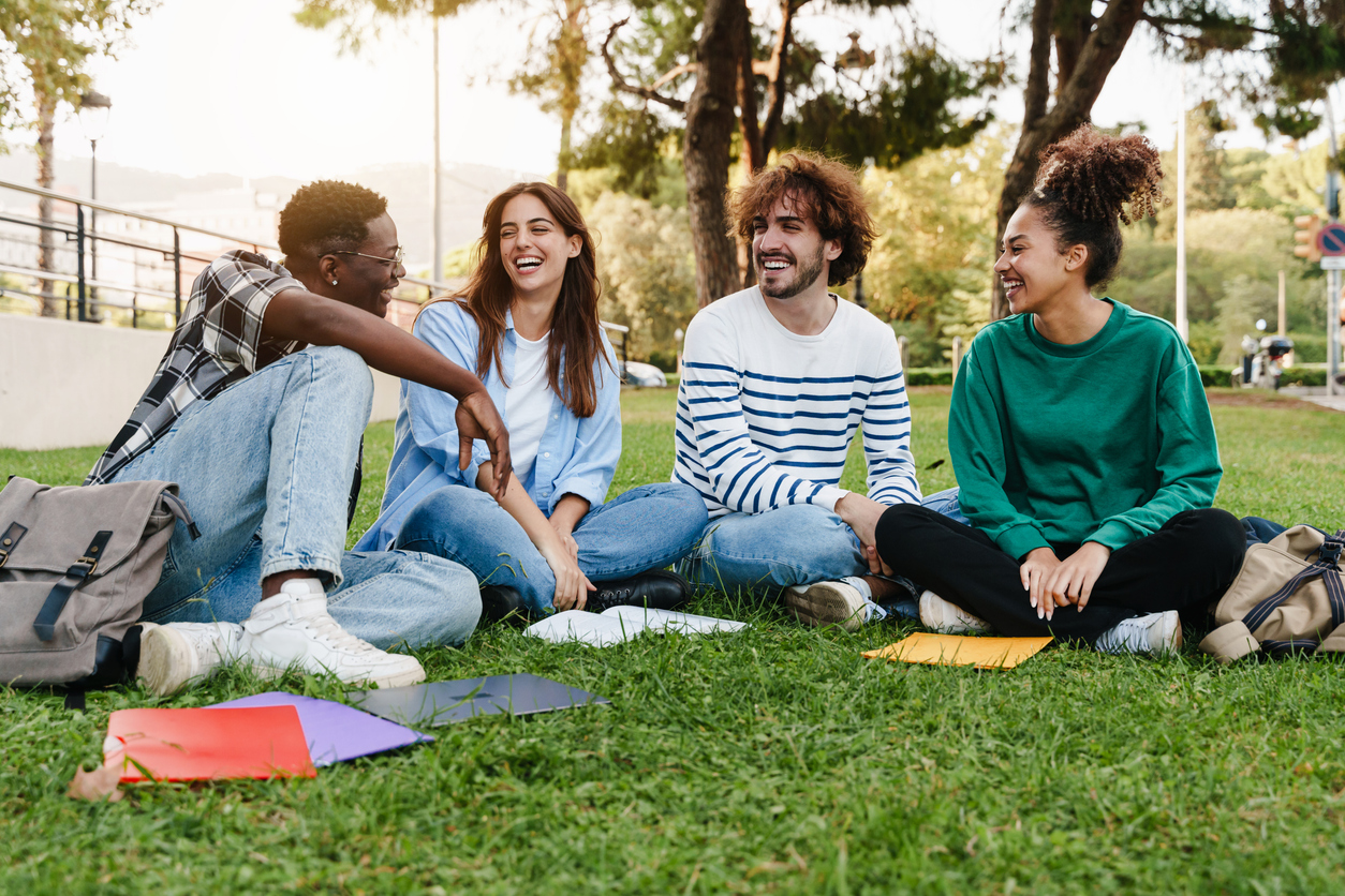 Four college students on a campus green.