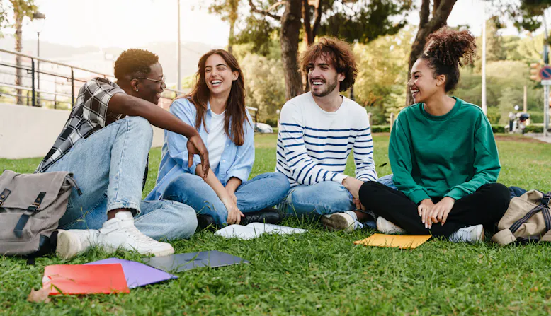 Four college students on a campus green.