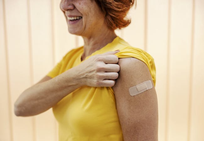 A woman shows her bandaid from a vaccine injection.