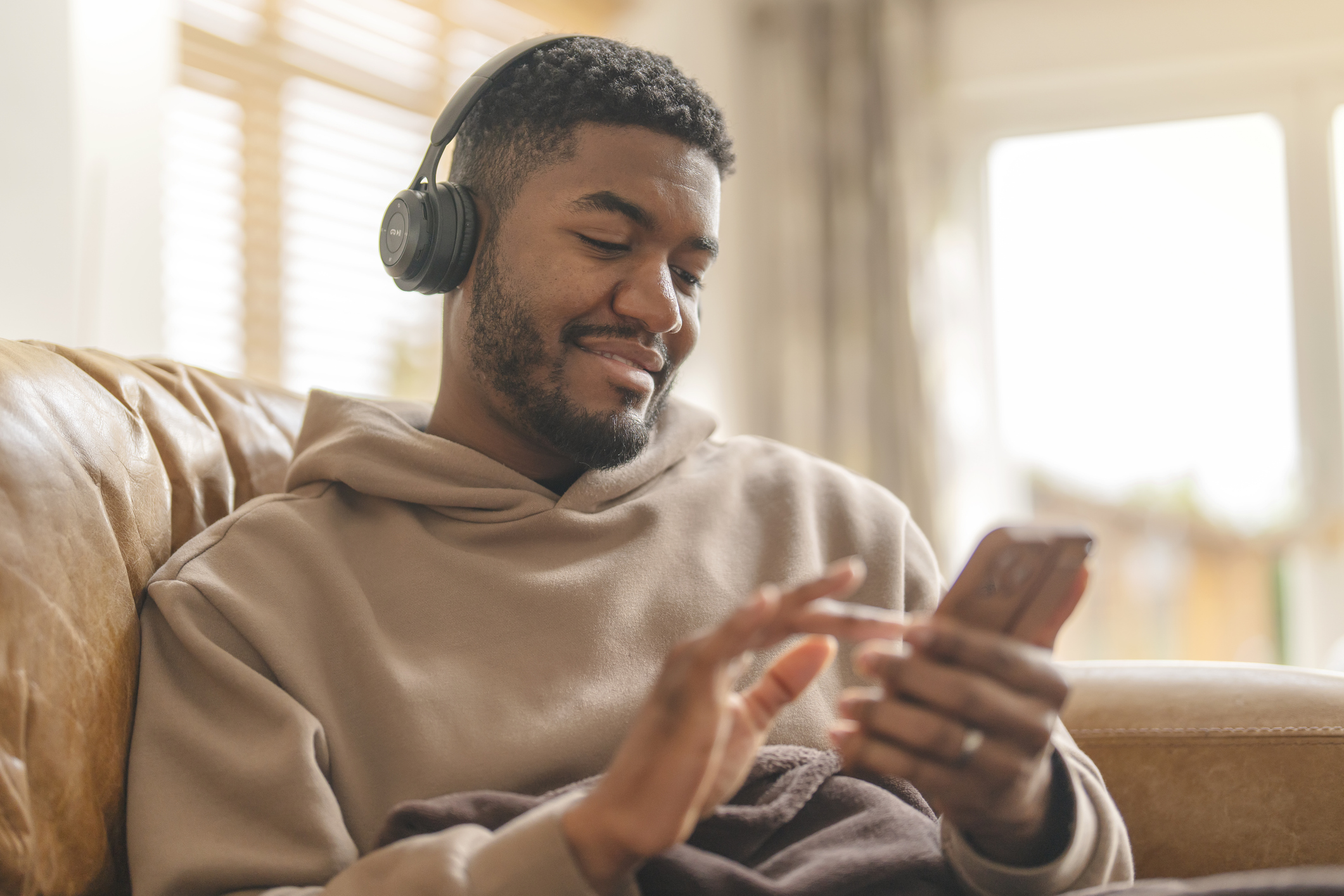 A Black man listens to a podcast with headphones.