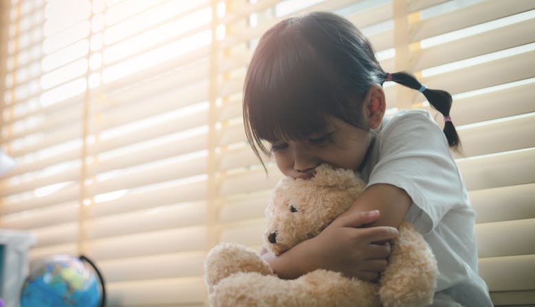 A sad child deals with emotions while hugging a teddy bear.