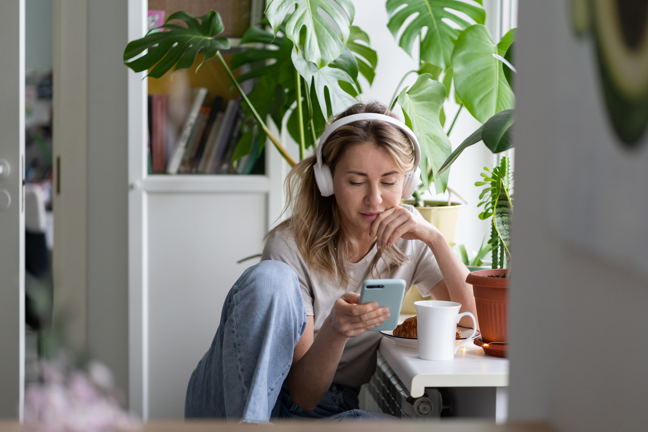 A young woman listens to a podcast on headphones