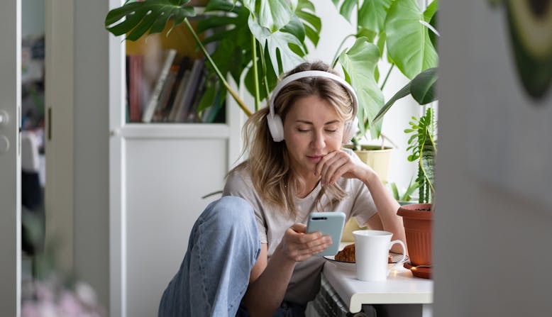 A young woman listens to a podcast on headphones