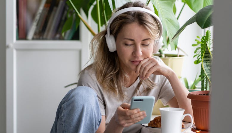 A young woman listens to a podcast on headphones