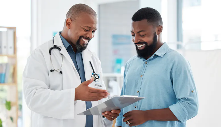 A doctor talks with a patient over a clipboard.
