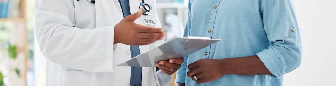 A doctor talks with a patient over a clipboard.