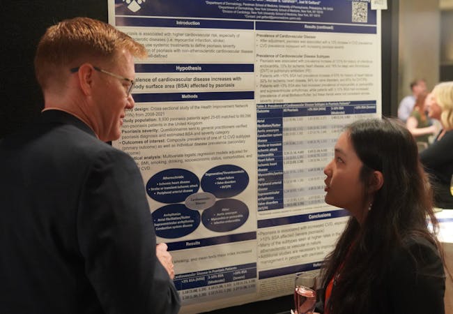 Guy Eakin and a resident read a poster on psoriatic disease research.