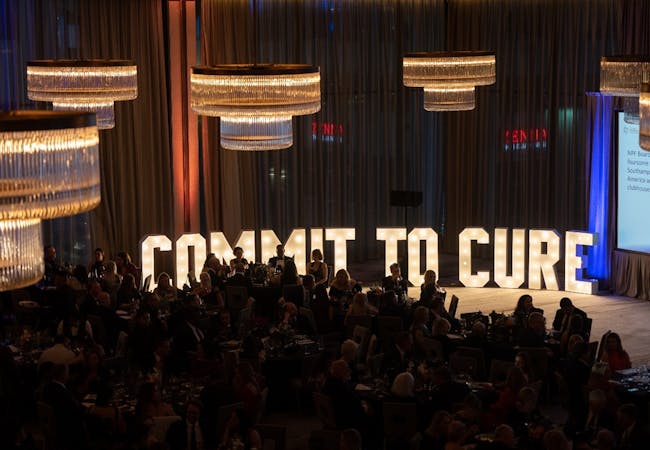 "Commit to Cure" spelled out in light-up letters on a stage.