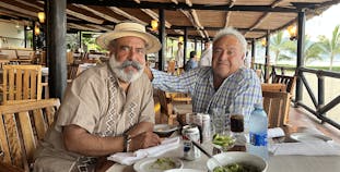 Humberto sits with a friend at a restaurant.