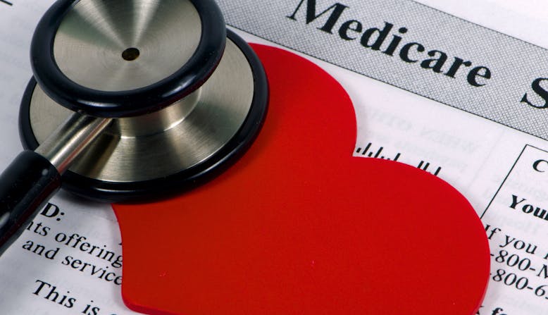 Paperwork with the word "Medicare" covered by a paper heart and a stethoscope.