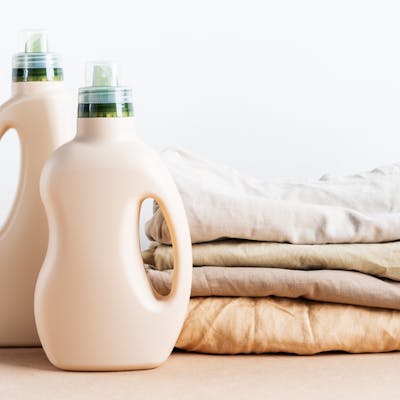 Bottles of laundry detergent next to a pile of laundry.