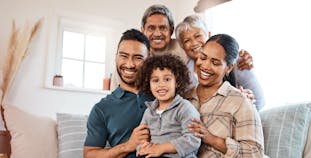 A multigenerational family sits on a couch and poses.