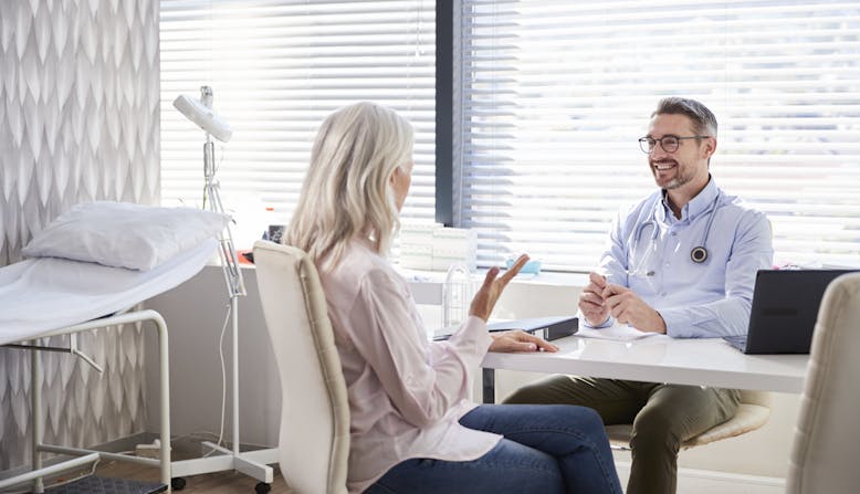 A doctor explains something to a patient in an office.