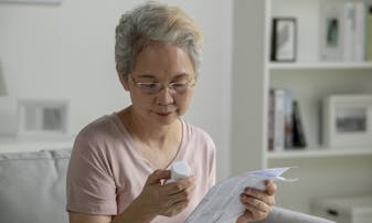 An older woman reads the prescription information document.