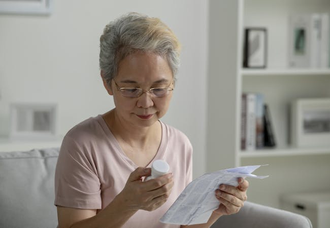 An older woman reads the prescription information document.
