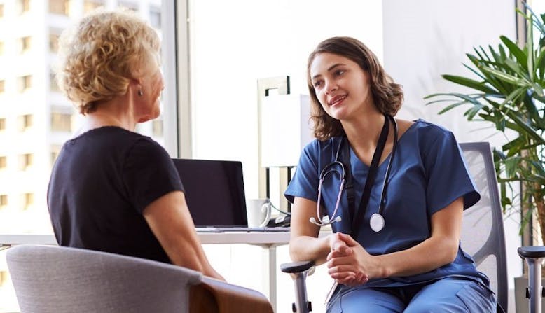 A doctor and patient discussing psoriatic disease in an office setting. 