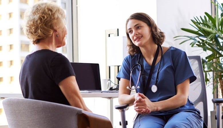 A doctor and patient discussing psoriatic disease in an office setting. 