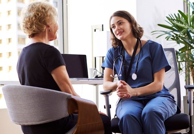 A doctor and patient discussing psoriatic disease in an office setting. 