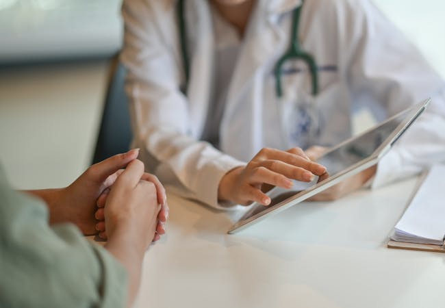 A doctor showing a patient something on a tablet.