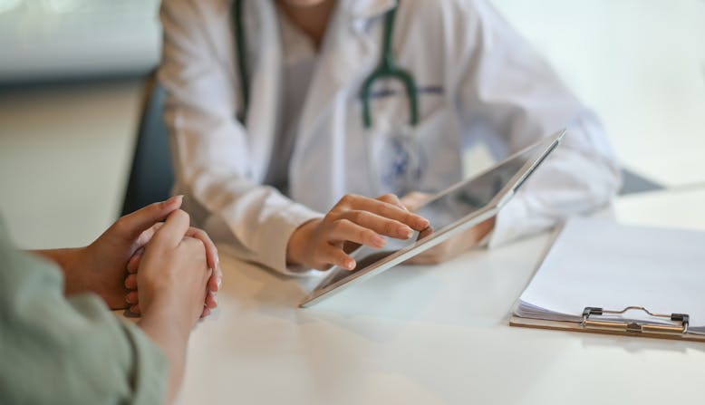A doctor showing a patient something on a tablet.