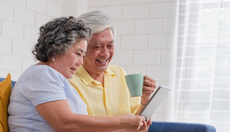 A man and a woman comparing insurance options on a tablet while sitting down.