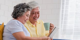 A man and a woman comparing insurance options on a tablet while sitting down. 