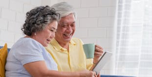 A man and a woman comparing insurance options on a tablet while sitting down.