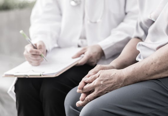 A doctor and patient discuss the findings of a chart while sitting down. 