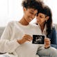 Two women embrace as they look at a sonogram of a fetus.
