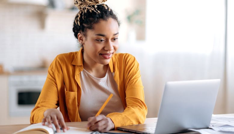 A woman with skin of color is studying with a laptop computer.