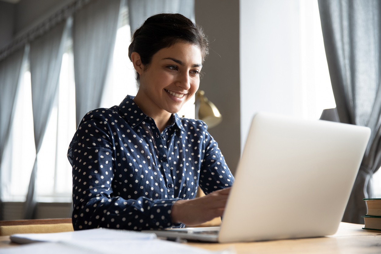 A woman working on a laptop at a table.